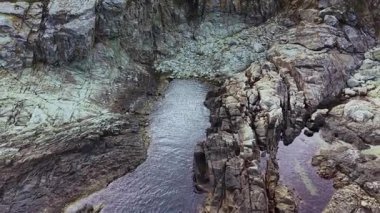 Havadan bakıldığında engebeli uçurumlar ve sakin sular gözlerden uzak bir kıyı manzarasında dramatik kaya oluşumları arasında yer alıyor..