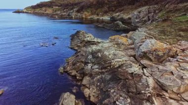 Bu hava perspektifi kayalık bir sahil şeridinin engebeli güzelliğini yakalar. Taşlar, parlak bir gökyüzünün altında sakin sularla buluşur ve doğanın sanatsal özelliklerini gösterir..
