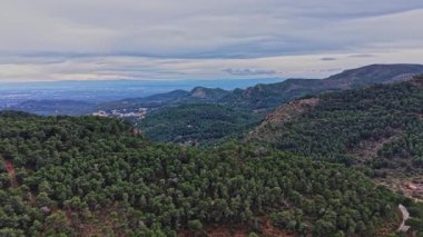Manzara İspanya 'daki yeşil tepeleri ve ağaçları gösteriyor. Bulutlu bir gökyüzünün altında uzak dağlar belirir. Manzara, doğanın bu alandaki güzelliğini gözler önüne sererek çok uzaklara uzanır..