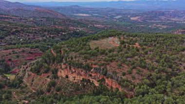 İspanya 'da insanlar yeşil tepelerden geçiyorlar. Manzara, açık bir gökyüzünün altındaki ağaçlar ve kayalık alanlarla dolu. Uzakta dağlar belirir, doğanın güzelliğini gösterir..