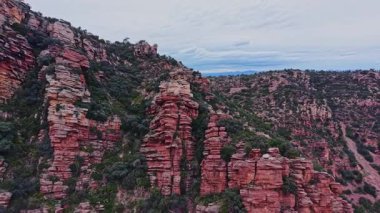 İspanya 'da, kayalık kayalıklar bulutlu gökyüzüne karşı dik bir şekilde yükselir. Manzara, bu açık hava ortamında doğal güzellikleri gösteren kırmızı taş ve yeşil bitki örtüsü katmanlarını gösteriyor..
