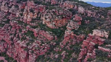 Ziyaretçiler öğleden sonra İspanya 'daki büyük kırmızı kaya oluşumlarına bakıyorlar. Bölge yeşil bitkiler ve engebeli arazilerle dolu. Manzara doğal manzara ve renkleri gösteriyor..