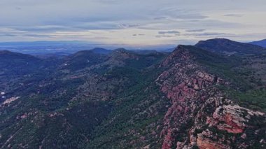 İspanya 'daki dağlar alacakaranlıkta görülebilir. Manzara yeşil ormanları ve kayalık oluşumları gösteriyor. Gökyüzü yumuşak bulutlarla berrak. Manzara alacakaranlıkta doğanın güzelliğini yakalar.