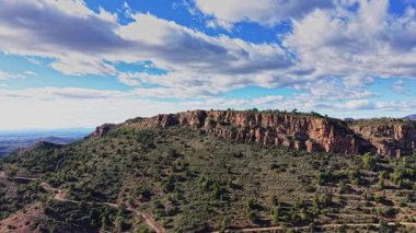 Bir grup insan İspanya 'da bir patikada yürüyüş yapmaktan hoşlanıyor. Mavi bir gökyüzünün altında kayalık uçurumlar yükseliyor. Yeşil bitki örtüsü tepeleri kaplıyor, güzel bir manzara yaratıyor..