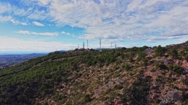 İspanya 'daki dağların manzarasında yeşil ağaçlar ve radyo kuleleri bulunur. Manzara açık mavi bir gökyüzünü ve gün boyunca bulutları gösteriyor. Sahneye doğal bir güzellik katıyor..