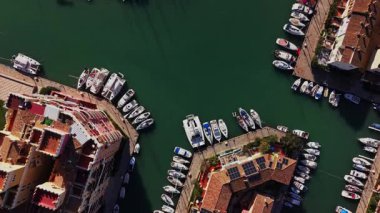 Birçok tekne İspanya 'da marinaya yanaştı. Suyun etrafında farklı tasarımlara sahip binalar var. Gökyüzü açık ve deniz kenarındaki bu işlek alanda güneş parlıyor..