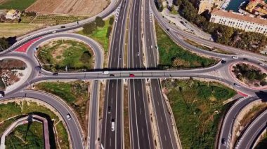 İspanya 'da büyük bir kavşakta trafik birden fazla şeritten geçiyor. Arabalar gün içinde bölgedeki yoğun yaşamı gösteren farklı yollarda gidiyorlar. Yolları çevreleyen yeşil alanlar.