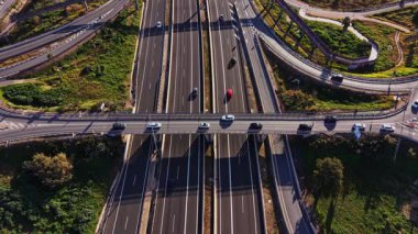 İspanya 'da otoyollar boyunca arabalar hareket eder. Görüntü birden fazla şerit ve üst geçit gösteriyor. Gün ortasındayız ve yollar farklı yönlere giden araçlarla dolu..
