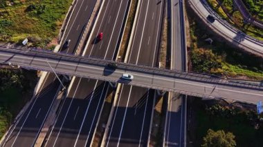 Araçlar İspanya 'da yoğun otoyollarda seyahat ederler. Yollar, gün boyunca açık gökyüzünün altında farklı yönlere hareket eden arabalarla trafiğin karışımını gösteriyor..