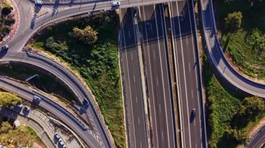 Arabalar İspanya 'da birden fazla otoyolda seyahat ederler. Olay yeri yeşilliklerle çevrili bir yol ağını gösteriyor. Hava açık ve yollar araçlarla dolu..