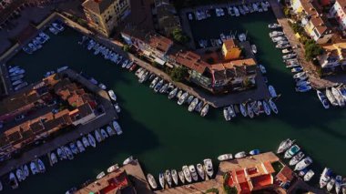 İspanya 'da bir marinaya birkaç tekne yanaştı. Manzara yeşil suyu ve suyu kaplayan binaları gösteriyor. Bu sahne, sahilin yakınındaki yoğun bir bölgedeki günlük yaşamı yakalar..