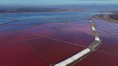 İşçiler, minerallerin zengin renkleriyle dolu bir tuz dairesinde meşguller. Kurulum büyük buharlaşma göletlerini ve temiz bir gökyüzünün altındaki manzaraları gösteriyor..