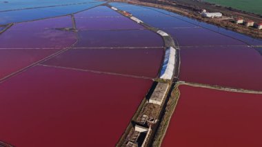 İşçiler renkli suyla dolu tuz tarlalarını yönetiyorlar. Bu tuz üretim alanı kırsal bir alanda yer almaktadır ve gündüz boyunca aktiftir..