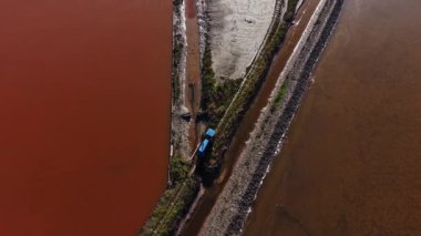 Kurutulmuş tuz düzlüklerini, su kanallarını ve gün içinde bölgede çalışan küçük mavi bir aracı gösteren hava görüntüsü.