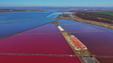 İşçiler mavi ve kırmızı suyu olan renkli tuz düzlüklerinde tuz toplarlar. Sahne, tuz ve suyun belirli bir yerde oluşturduğu benzersiz desenleri gösteriyor..