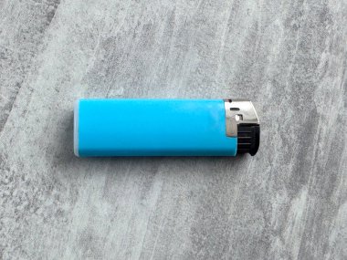 Gri bir yüzeyde parlak mavi bir çakmak var. İyi aydınlatılmış bir alanda konumlandırılmıştır. Çevre basit ve asgari düzeyde. Daha hafif olana odaklanmamızı sağlıyor..