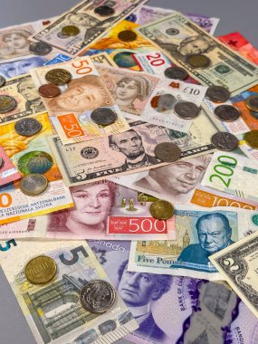 Masaya farklı ülkelerden çeşitli banknotlar ve madeni paralar yayılıyor. Koleksiyonda dolar, avro ve pound gibi para birimleri gösteriliyor..