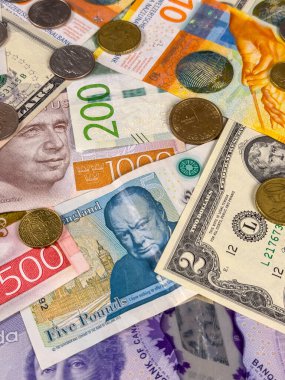 Çeşitli banknotlar ve madeni paralar düz bir zeminde, farklı ülke ve bölgelerden gelen farklı para birimlerini, farklı değerlerden gelen banknotları ve sikkeleri sergiliyor..