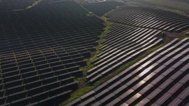 Güneş panelleri açık arazide sıra sıra dizilir. Güneş ışığını yakalamak ve enerji üretmek için konumlandırıldılar. Konum, güneş teknolojisinin elektrik üretimi için geniş çapta kullanıldığını gösteriyor..