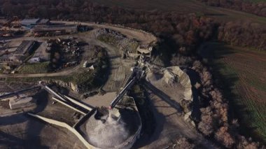 Malzemeleri çıkarmak ve işlemek için çalışan çeşitli makinelere sahip bir taş ocağı. Taşıyıcılar, mayınlı kaynakları gün ışığında bölgedeki farklı noktalara taşıyorlar..