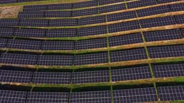 Güneş panelleri bir güneş çiftliğinde sıra sıra kurulur. Kurulum, enerji üretimi için güneş ışığını emmek üzere hizalanmış birçok paneli gösteren geniş bir arazi alanını kapsıyor..