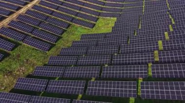 Güneş panelleri geniş bir alanda sıra sıra dizilir. Bu site yenilenebilir enerji üretimine odaklanıyor ve sürdürülebilir enerji için modern teknoloji kullanımını gösteriyor.