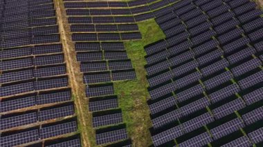 Güneş panelleri tarlalarda geniş bir tarlayı kaplıyor. Paneller düzgün bir şekilde hizalanır, güneş ışığını yakalar ve kullanmak için enerji üretir..