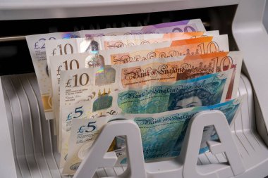 İngiliz sterlin banknotları bir para çekme makinesi tarafından işleniyor. Makine, mali bir ortamda takas amacıyla farklı mezhepleri sınıflandırır.
