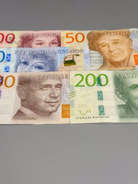 Farklı değerlere sahip İsveç banknotları pürüzsüz bir yüzeye serilmiştir. Notlar arasında 50, 100, 200 ve 2000 kronluk banknotlar tasarım ve değer sergilenmektedir..