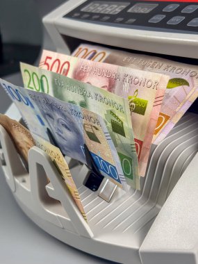 Bir para sayma makinesi İsveç kronlarını çeşitli değerlerden işliyor. Makine, bir finans ortamında paraları sayarken notaları gösterir.