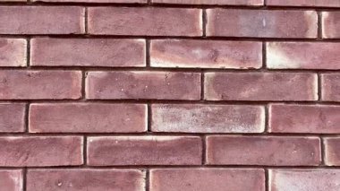 Gerçekçi dokusu ve doğal ışığı olan kırmızı tuğlalı bir duvarın hareketli görüntüsü. Tasarım ve inşaat projelerinde arka plan videosu, doku görüntüsü için ideal.