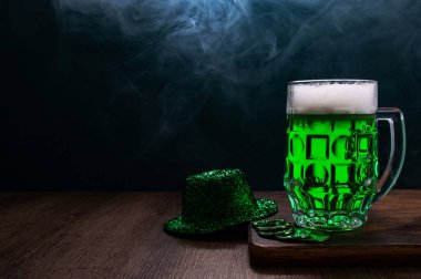 Yeşil bira, şapka ve yonca yaprakları gri ahşap masada. Aziz Patrick Günü 20.