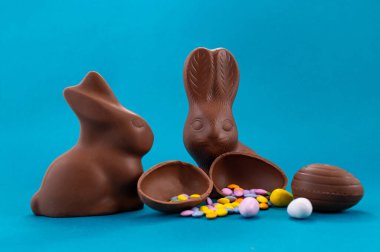 Paskalya kutlaması. Şirin çikolatalı tavşanlar ve açık mavi arka planda yumurta.