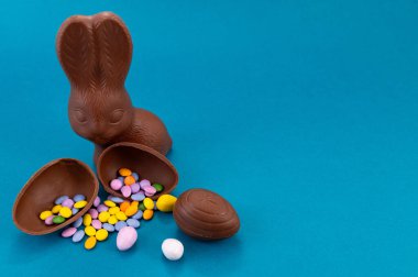 Paskalya kutlaması. Şirin çikolatalı tavşanlar ve açık mavi arka planda yumurta.