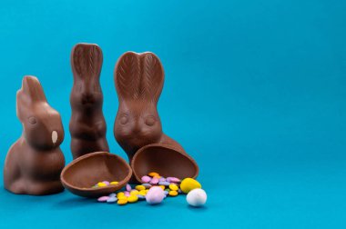 Paskalya kutlaması. Şirin çikolatalı tavşanlar ve açık mavi arka planda yumurta.