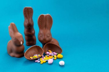 Paskalya kutlaması. Şirin çikolatalı tavşanlar ve açık mavi arka planda yumurta.