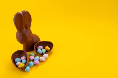 Çikolatalı Paskalya yumurtaları ve sarı arka planda fotokopi alanı olan çikolatalı tavşancık. 20