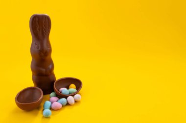 Çikolatalı Paskalya yumurtaları ve sarı arka planda fotokopi alanı olan çikolatalı tavşancık. 20