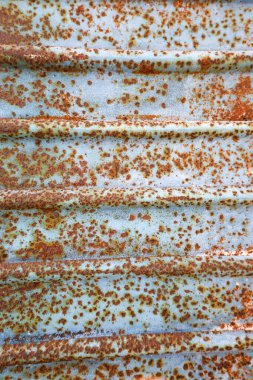 Yakın çekim, eski metal bir yüzey üzerindeki pasın karmaşık desenlerini yakalar. Hafif ışıkla aydınlatılan toprak rengi ve dokuların bir karışımını gösterir..