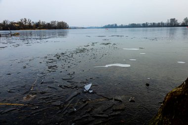 Kış mevsiminde kıyı kıyısında yüzen buz parçalarının olduğu kısmen donmuş bir göl..