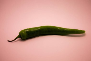 Taze yeşil kırmızı biber, koyu pembe bir arka plana karşı yatay olarak dinlenir..