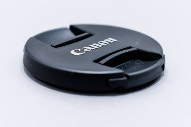 Beyaz arka planda duran siyah plastik bir Canon kamera kapağının yakın çekim çekimi..