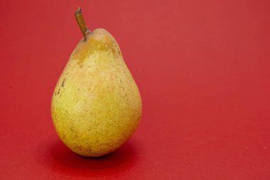 Tek bir olgun armut kırmızı bir zeminde oturur..
