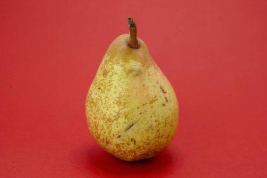 Tek bir armut kırmızı bir zeminde oturur..