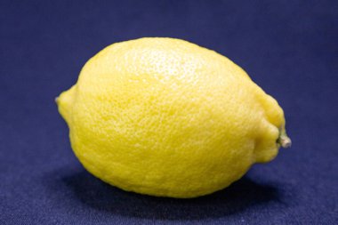 Koyu mavi bir yüzey üzerinde taze sarı limon. Mutfak kullanımına ya da ferahlatıcı bir içeceğe hazır..