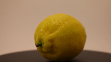 Taze sarı bir limon, parlak rengini ve doğal dokusunu sergileyerek koyu bir yüzeyde zarifçe oturur. Basitliğin büyüleyici özü günlük güzelliği ve tazeliği vurgular..