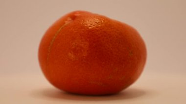 Yumuşak bir zemine karşı parlak, olgun bir mandalinanın yakından görüntüsü. Dokusunun ve renginin ayrıntıları tazeliğini ve çekiciliğini vurguluyor..