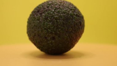 Canlı renkli bir avokado parlak sarı bir yüzey üzerinde yer alır. Eşsiz dokusu, büyüleyici yeşil renklerini sergileyerek daha yakından incelemeye davet ediyor..