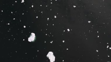 Kamera, uzak Icefjord 'a ve günbatımına doğru yükselmeden önce karanlık su ve buzun üzerine bakıyor. 