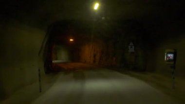 Aracın çıkışı yaklaştıkça, pürüzsüz bir taş tünel yavaş yavaş aydınlanıyor. Karlı dağlarla birlikte mavi-turuncu Norveç fiyortu gün batımını gözler önüne seriyor.. 